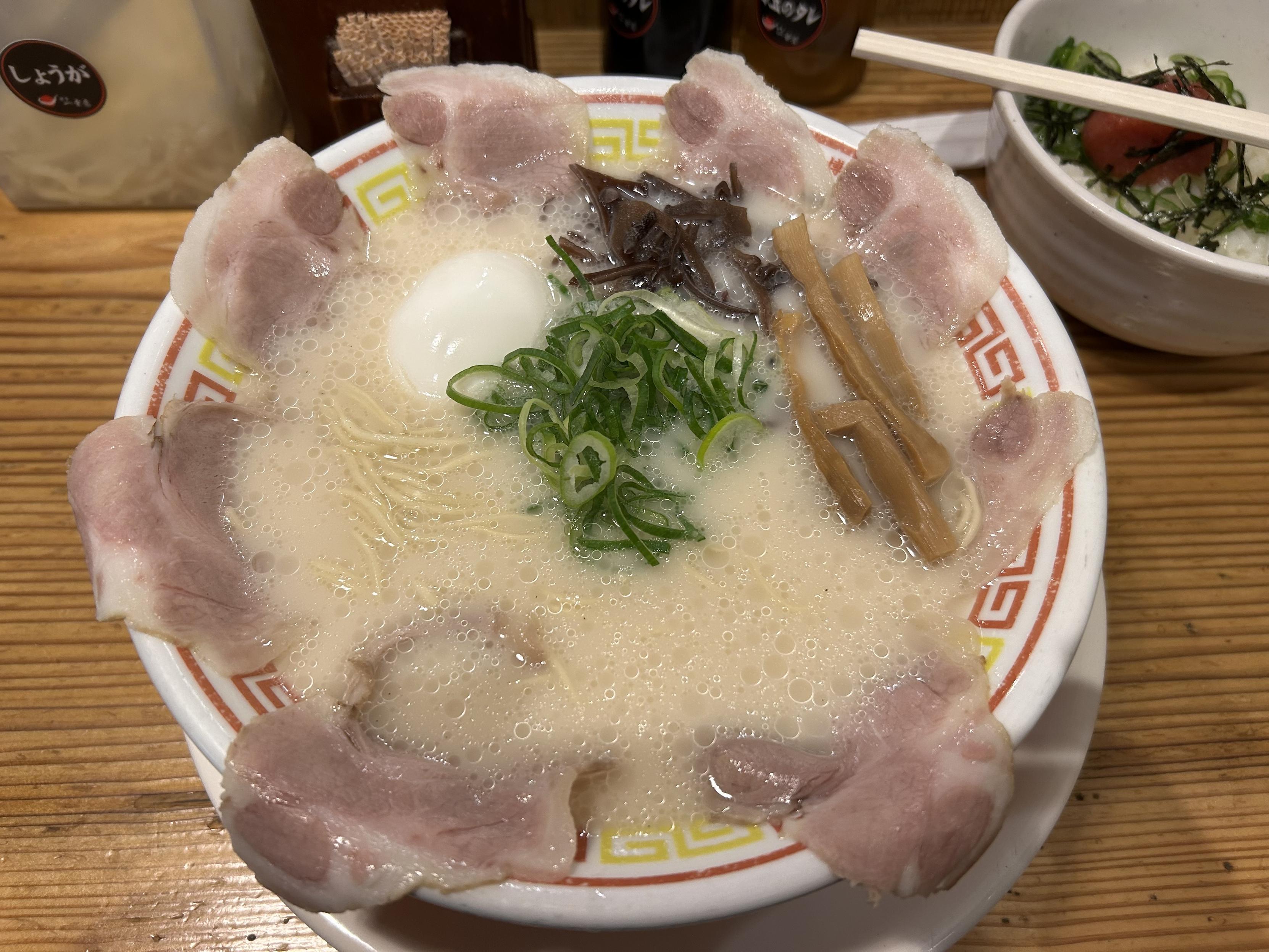 チャーシューとネギがたくさん乗った豚骨ラーメンが写っている
